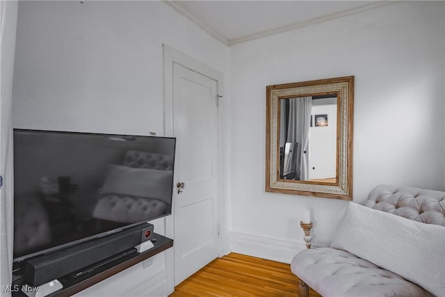 sitting room featuring ornamental molding, baseboards, and light wood-type flooring