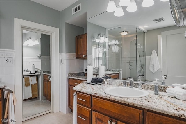 bathroom with tile patterned floors, visible vents, a stall shower, and vanity