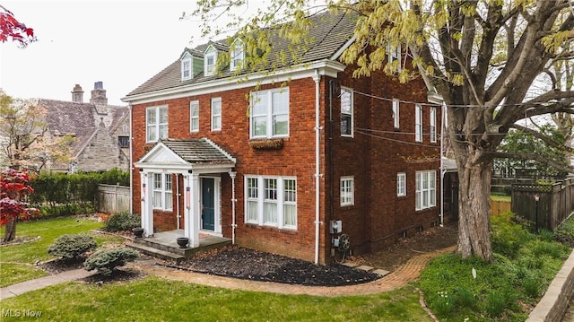 view of front of property with brick siding, fence, and a front yard