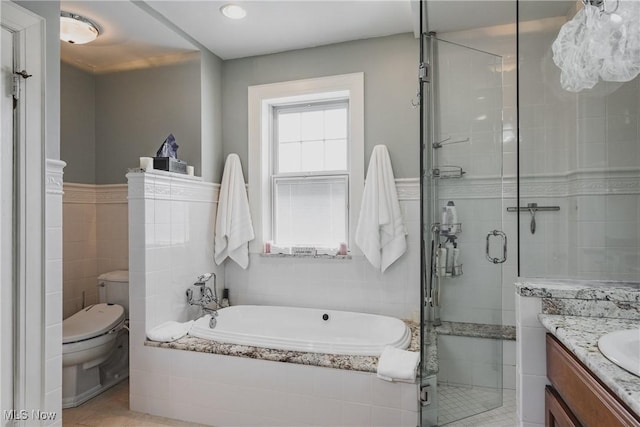 bathroom featuring toilet, a stall shower, a garden tub, and vanity