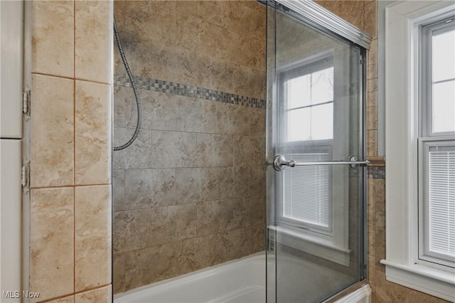 bathroom featuring bath / shower combo with glass door and a healthy amount of sunlight