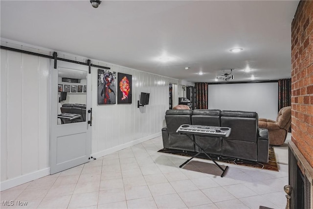 living area featuring a barn door, brick wall, a decorative wall, and baseboards