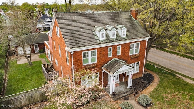 view of front facade featuring fence, a front lawn, a chimney, and brick siding