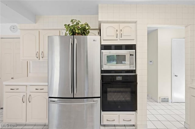 kitchen featuring light tile patterned floors, light countertops, freestanding refrigerator, built in microwave, and oven