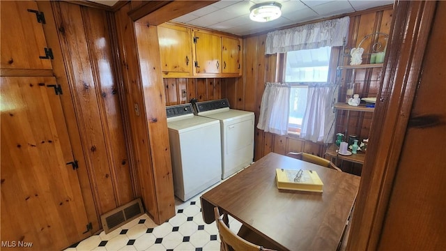 laundry room featuring visible vents, wooden walls, washer and clothes dryer, cabinet space, and light floors