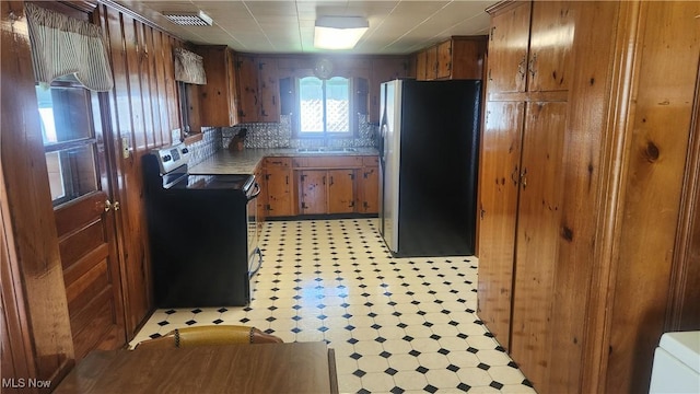 kitchen with a sink, brown cabinets, visible vents, black electric range, and freestanding refrigerator