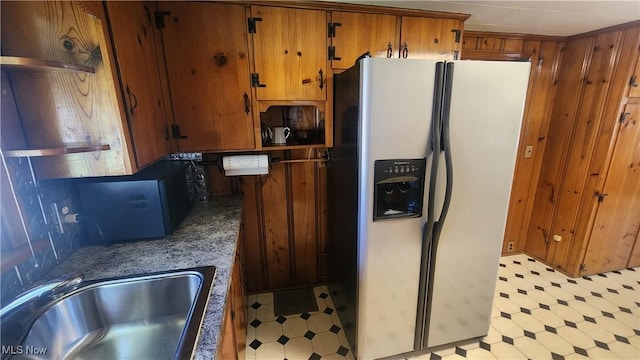 kitchen with fridge with ice dispenser, a sink, brown cabinets, and light floors