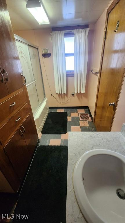 full bath with vanity, bath / shower combo with glass door, and tile patterned floors