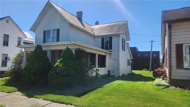 view of side of home with a chimney and a lawn