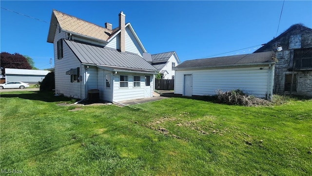 rear view of house with metal roof, a lawn, and a chimney