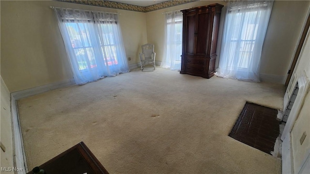 empty room with a healthy amount of sunlight, baseboards, and carpet floors