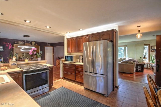 kitchen with appliances with stainless steel finishes, light tile patterned floors, light countertops, and pendant lighting