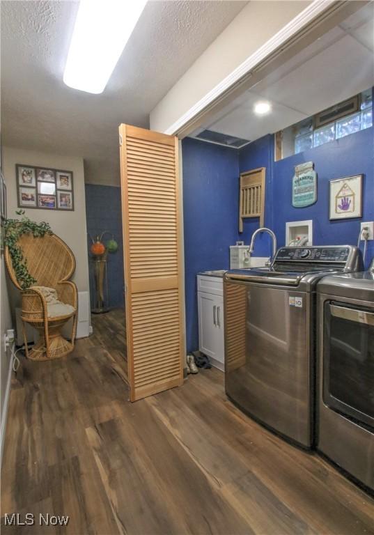 laundry area with a textured ceiling, wood finished floors, and washing machine and clothes dryer