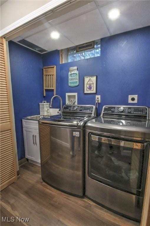 laundry area with dark wood finished floors, cabinet space, and separate washer and dryer