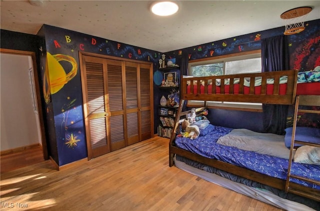 bedroom featuring wallpapered walls, wood finished floors, and a closet