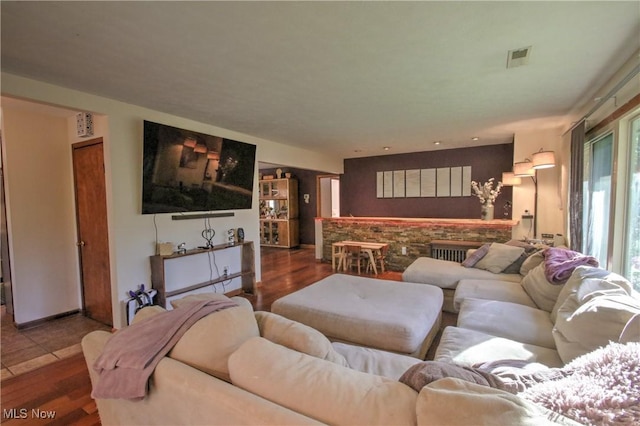 living room with wood finished floors, visible vents, and a bar