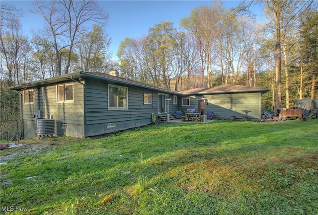 back of property with a chimney, central AC unit, and a yard