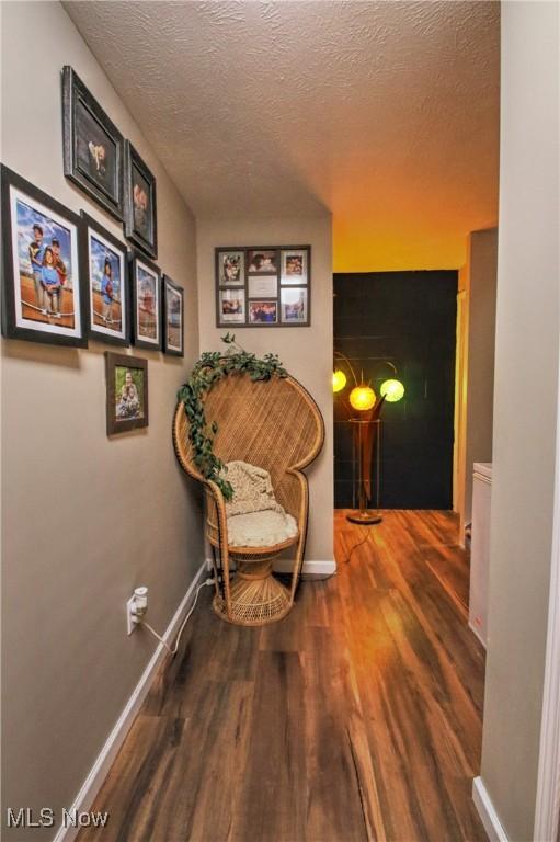 living area with a textured ceiling, wood finished floors, and baseboards