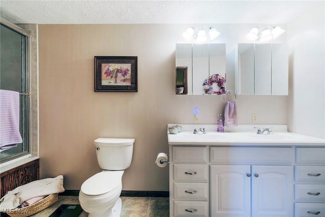full bathroom featuring double vanity, a shower with door, toilet, baseboards, and a sink