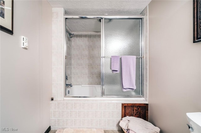 full bath with tiled shower / bath, toilet, and a textured ceiling