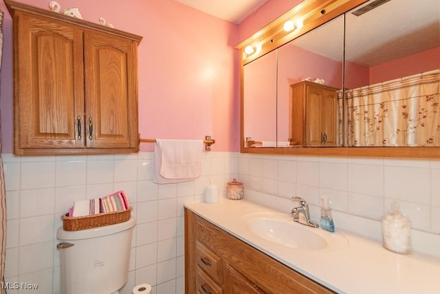 full bathroom with toilet, wainscoting, and vanity