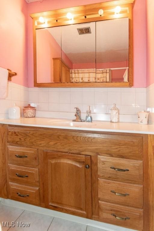 bathroom with vanity, tile patterned flooring, and backsplash