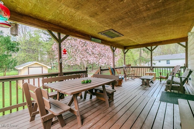 wooden terrace featuring outdoor dining area and an outbuilding