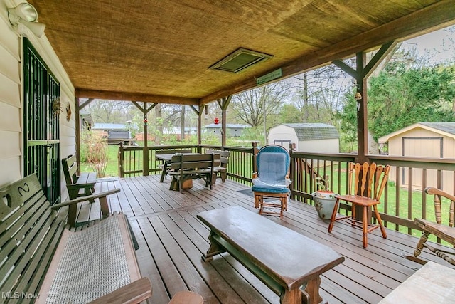 wooden deck featuring a storage shed, a yard, and an outdoor structure