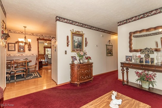 interior space with a textured ceiling, baseboards, a notable chandelier, and carpet floors