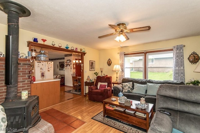 living area featuring wood finished floors, ceiling fan, and a wood stove