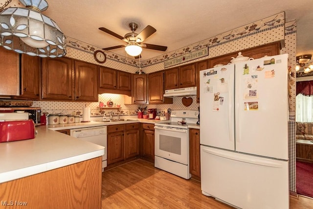 kitchen featuring white appliances, light wood-style floors, under cabinet range hood, ceiling fan, and a sink