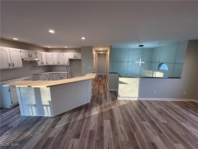 kitchen featuring white cabinetry, a kitchen island, dark wood-style floors, and baseboards