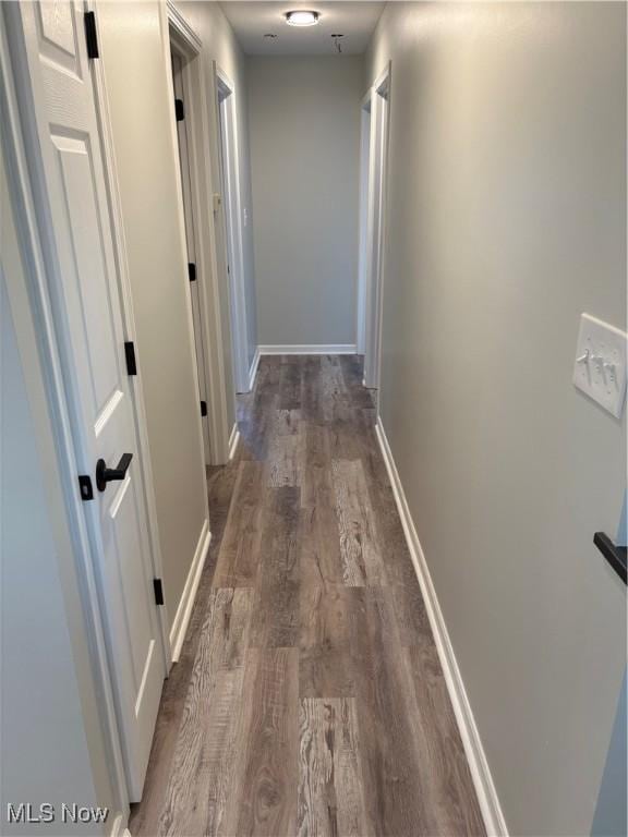 hall with dark wood-style flooring and baseboards
