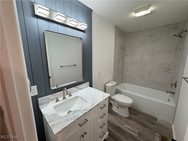 full bath with wood finished floors, toilet, shower / washtub combination, vanity, and a textured ceiling