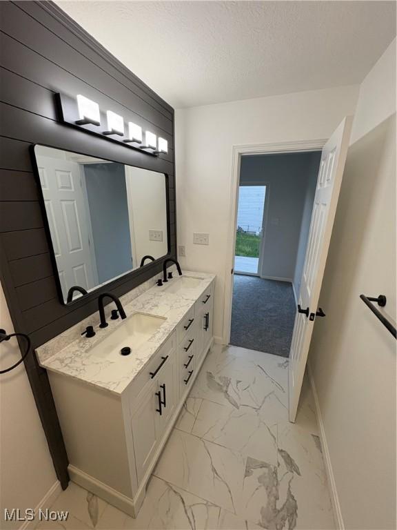 bathroom featuring marble finish floor, a sink, and baseboards