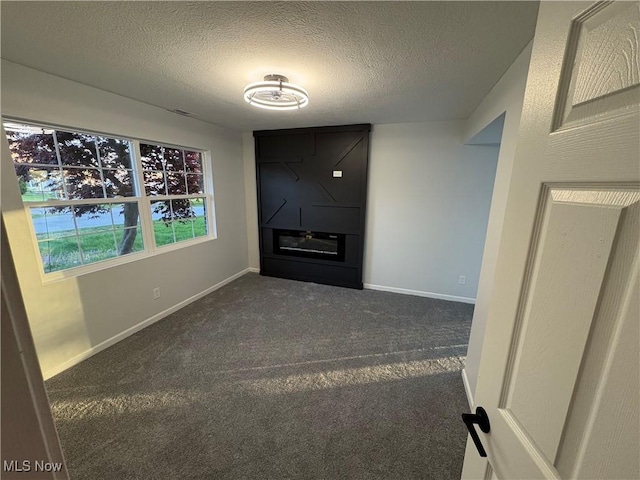 unfurnished living room featuring a textured ceiling, carpet flooring, and baseboards