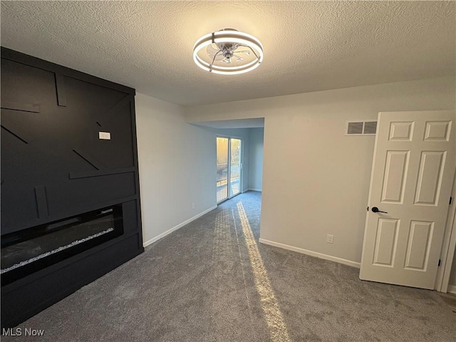 unfurnished living room featuring baseboards, visible vents, carpet floors, and a textured ceiling