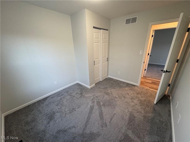 unfurnished bedroom with a closet, visible vents, carpet, and baseboards