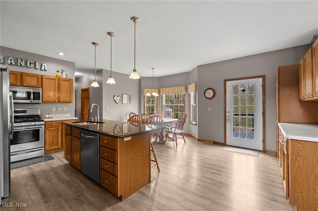 kitchen featuring a sink, appliances with stainless steel finishes, brown cabinetry, and wood finished floors