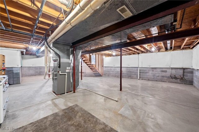unfinished below grade area featuring stairs, heating unit, and visible vents