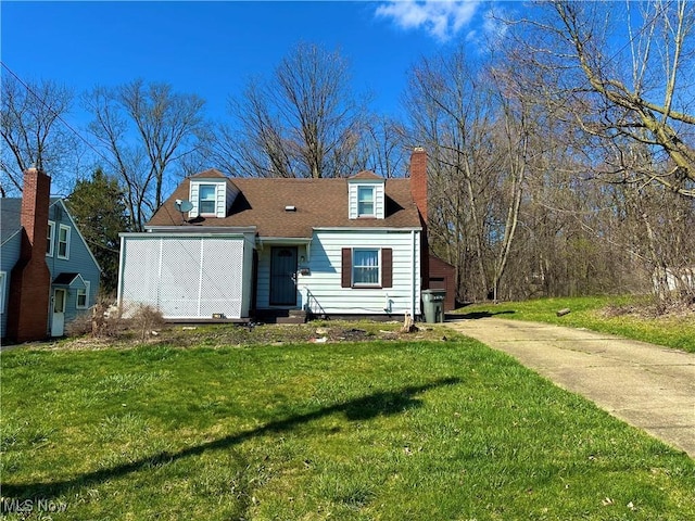 view of front of house featuring a chimney, concrete driveway, and a front lawn