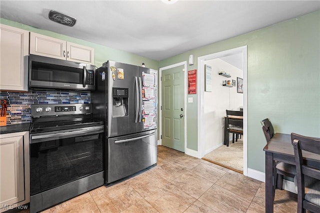 kitchen featuring tasteful backsplash, dark countertops, stainless steel appliances, visible vents, and baseboards
