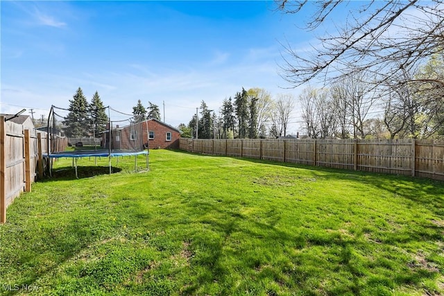 view of yard featuring a trampoline and a fenced backyard