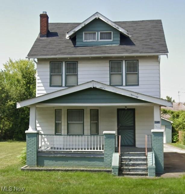 traditional style home featuring covered porch, a chimney, and a front lawn