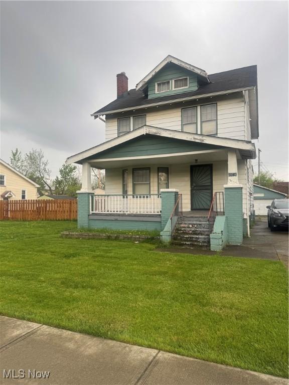 traditional style home with a porch, fence, a chimney, and a front yard