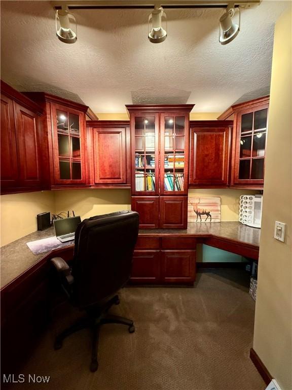 7455 Brushmore Ave NW, North Canton, OH 44720 - office area featuring built in desk, a textured ceiling, and dark colored carpet