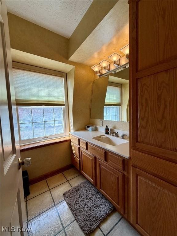 bathroom featuring a textured ceiling, a healthy amount of sunlight, vanity, and tile patterned flooring