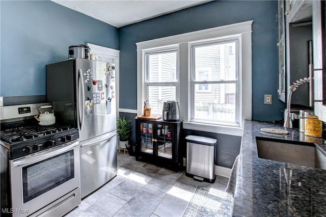 kitchen with dark stone counters, appliances with stainless steel finishes, and baseboards