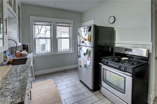 kitchen with glass insert cabinets, light stone counters, appliances with stainless steel finishes, backsplash, and a sink