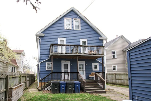 rear view of property featuring a fenced backyard and a balcony